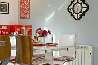 a dining room with a table and chairs and a clock at Hill Head Cottage in Saint Columb Major
