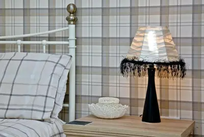 a lamp on a wooden table next to a bed at Hill Head Cottage in Saint Columb Major