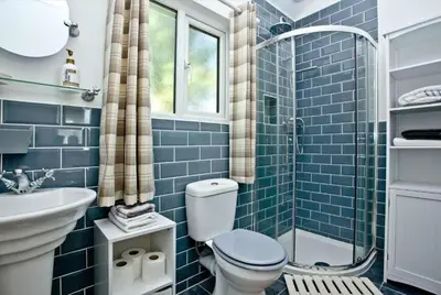 a blue tiled bathroom with a toilet and a shower at Hill Head Cottage in Saint Columb Major