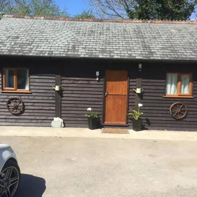 a house with a wooden door and a porch at Hill Head Cottage in Saint Columb Major