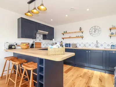 a kitchen with blue cabinets and a counter with stools at Chi an Mor in Penzance