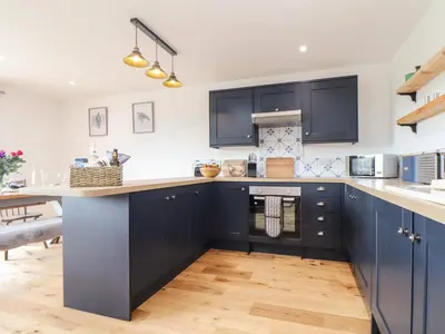 a kitchen with navy blue cabinets and wooden floors at Chi an Mor in Penzance