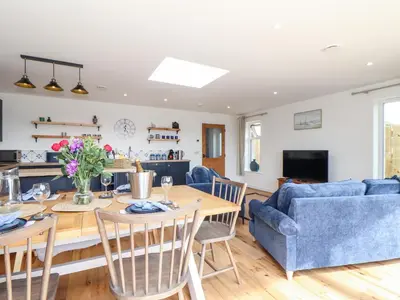 a dining room and living room with a table and chairs at Chi an Mor in Penzance