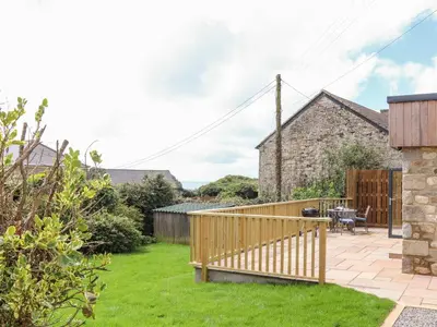 a garden with a wooden deck and a patio at Chi an Mor in Penzance