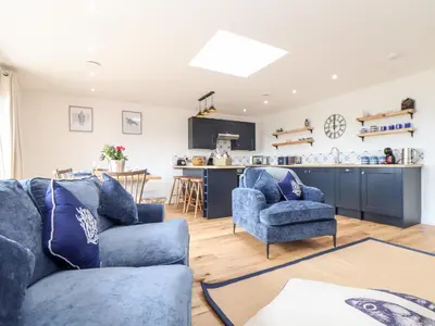 a living room with two blue chairs and a kitchen at Chi an Mor in Penzance