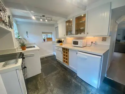 a kitchen with white cabinets and a white microwave at Brook Cottage is a traditional fisherman's cottage in Port Isaac