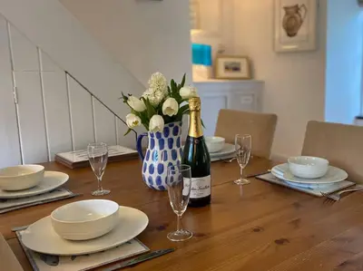 a table with a bottle of champagne and a vase of flowers at Brook Cottage is a traditional fisherman's cottage in Port Isaac