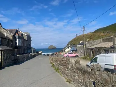 a street in a town with a pink car and the ocean at Fentrigan Manor Farm & Holiday Cottages in Bude