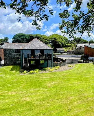 a barn with a green lawn in front of it at Fentrigan Manor Farm & Holiday Cottages in Bude