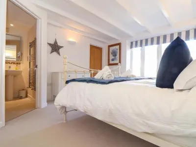 a bedroom with a large white bed with blue pillows at Potters Barn in Helston