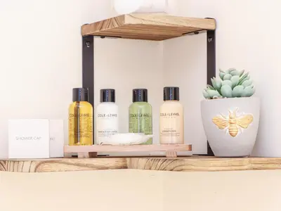 a shelf with four bottles of essential oils and a cactus at Potters Barn in Helston