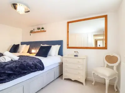 a bedroom with a bed and a mirror and a chair at Potters Barn in Helston