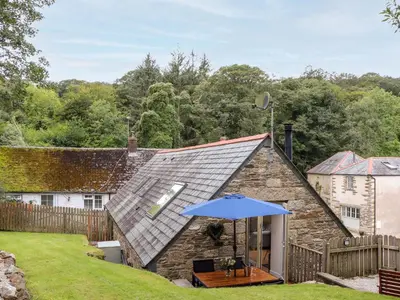 a house with an umbrella in a yard at Potters Barn in Helston