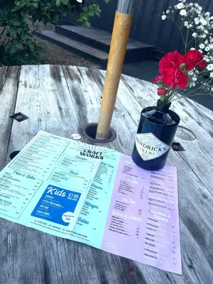 a table with a menu and a vase of flowers at Stones Throw Lodge in Padstow