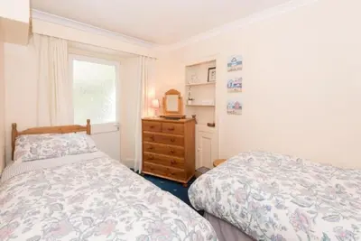 a bedroom with two beds and a dresser and a window at Quayview in Looe