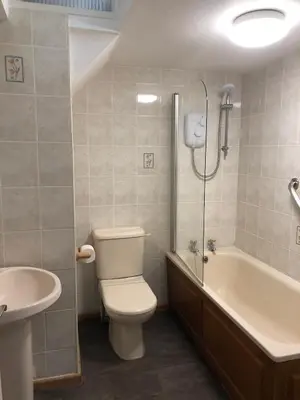 a bathroom with a toilet and a tub and a sink at Quayview in Looe