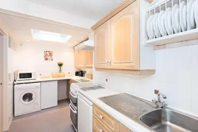 a white kitchen with a sink and a dishwasher at Quayview in Looe