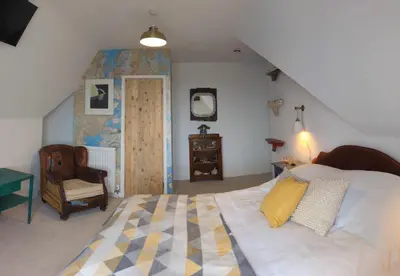 a bedroom with a large bed and a chair at Treheveras Guest House in Newquay