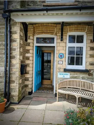 a blue door of a brick house with a bench at Treheveras Guest House in Newquay