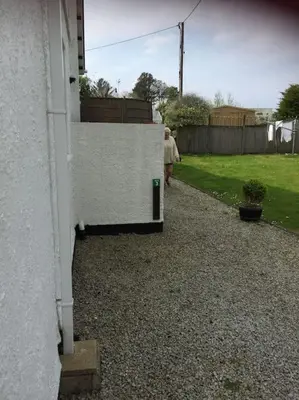 a woman walking down a sidewalk next to a house at Carbis Bay luxury ground floor flat close to beach in Carbis Bay