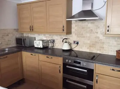a kitchen with wooden cabinets and a tea kettle at Carbis Bay luxury ground floor flat close to beach in Carbis Bay
