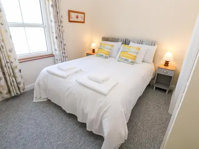 a bedroom with a white bed with two towels on it at The Mariners in Helston