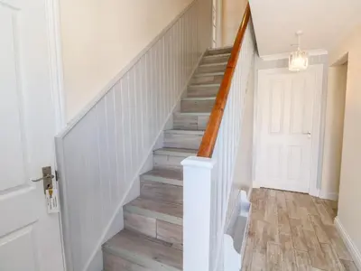 a staircase in a home with white walls and wood floors at The Mariners in Helston