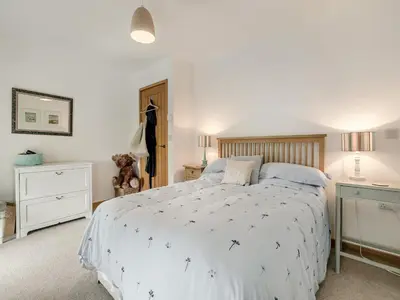 a bedroom with a bed with a white comforter at Myrtle Cottage in Saint Just in Roseland
