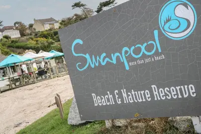 a sign at the beach with a resort at Albert's Den in Falmouth