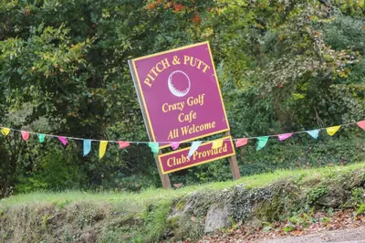 a sign for a curry goat cafe with bunting at Albert's Den in Falmouth