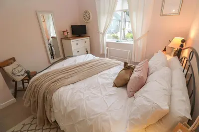 a bedroom with a bed with white sheets and a window at Albert's Den in Falmouth