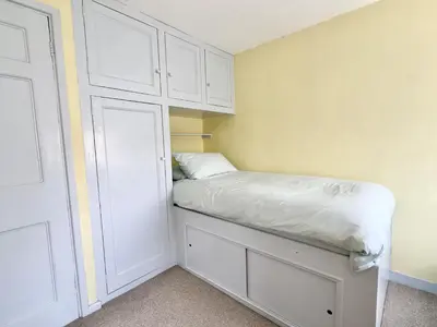 a small bedroom with a bed and white cabinets at Coswarth Cottage in Padstow
