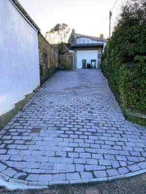 a brick driveway with a building and a garage at Coswarth Cottage in Padstow