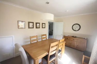 a dining room table with chairs and a clock on the wall at Coswarth Cottage in Padstow