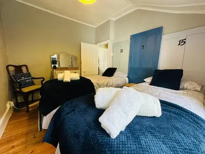 a bedroom with three beds with black and white sheets at Alexander cottage in Penryn
