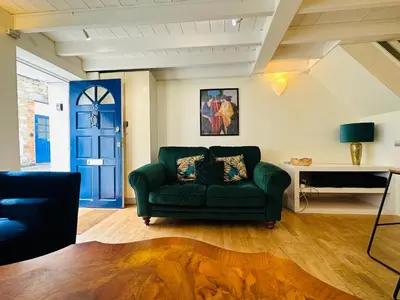 a living room with a green couch and a blue door at Alexander cottage in Penryn