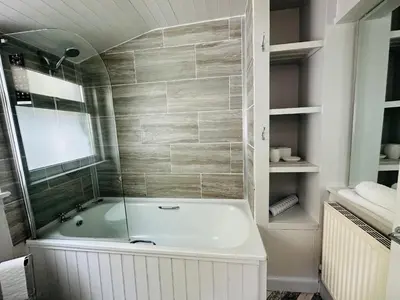 a bathroom with a bath tub with a window at Alexander cottage in Penryn