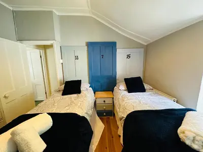 a bedroom with two beds and a blue door at Alexander cottage in Penryn