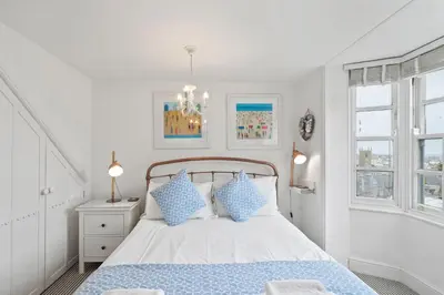 a white bedroom with a bed with blue pillows at Cottage By The Sea, Wi-Fi, Pets Accepted in St Ives