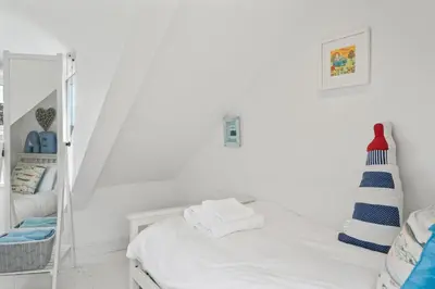 a white bedroom with a bed and a mirror at Cottage By The Sea, Wi-Fi, Pets Accepted in St Ives