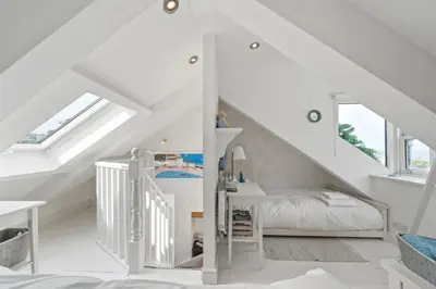a white attic bedroom with a bed and stairs at Cottage By The Sea, Wi-Fi, Pets Accepted in St Ives