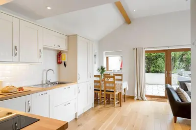 a kitchen with white cabinets and a dining room at Rosemerryn in Marazion