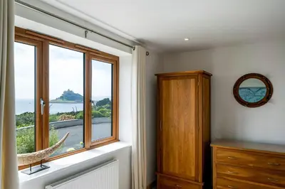 a bedroom with a window with a view of the ocean at Rosemerryn in Marazion
