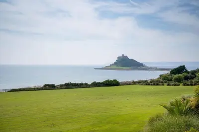 a green field with an island in the ocean at Rosemerryn in Marazion