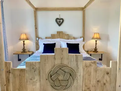 a bedroom with a large wooden bed with a rope on it at Mevagissey Boutique Flatlet with sea and countryside views in Mevagissey
