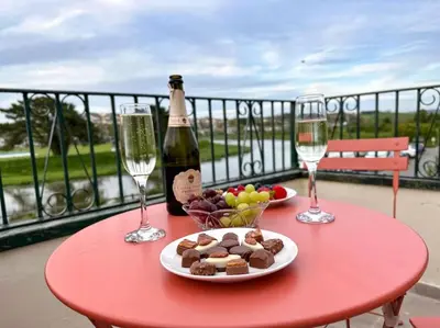 a red table with a plate of food and two wine glasses at Riverside home by Camel Trail in Cornwall in Wadebridge