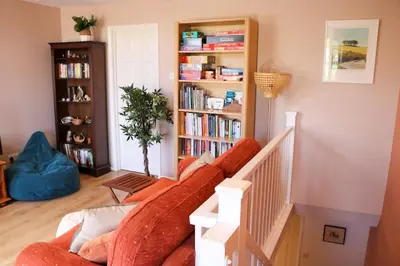 a living room with a couch and a book shelf at Riverside home by Camel Trail in Cornwall in Wadebridge