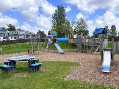 a park with a playground with a slide and benches at Riverside home by Camel Trail in Cornwall in Wadebridge