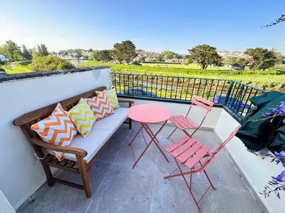 a bench and two chairs and a table on a balcony at Riverside home by Camel Trail in Cornwall in Wadebridge