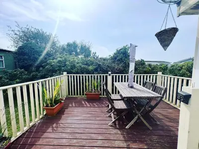 a wooden deck with a table and chairs on it at Seven Bays Holiday Home in Padstow
